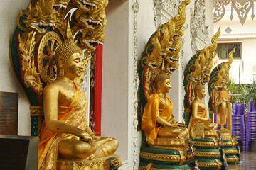 A group of Buddha statues in various postures with a serpent covering the top. Decorated around the chapel at Wat Naga Prok Temple. Located at Bangkok capital city in Thailand.