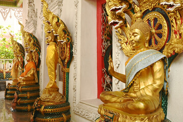A group of Buddha statues in various postures with a serpent covering the top. Decorated around the...