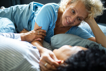 Middle aged lesbian couple cuddling in bed