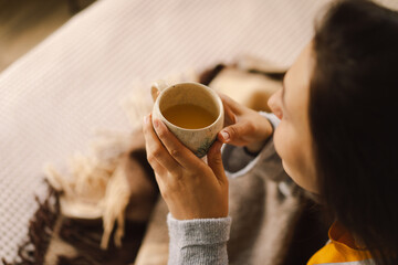 A woman relaxes in a bright, serene room, sipping coffee while focused on her book. The natural...
