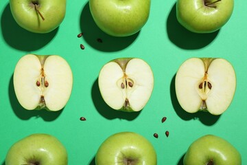 Flat lay composition with whole, cut apples and seeds on green background