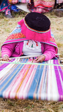 Andean woman in pink weaving alpaca textiles
