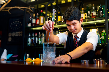 Professional male bartender preparing and serving cocktail drink to customer on bar counter at luxury nightclub. Barman making mixed alcoholic drink for celebrating holiday party at restaurant bar.