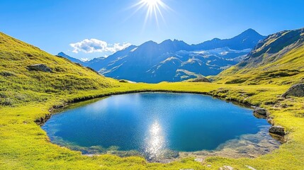 Obraz premium A serene mountain lake with crystal clear water reflects the sun on a bright, sunny day, surrounded by green grass and towering mountains.