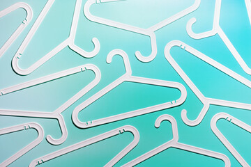White Clothes hangers as creative minimal composition on pastel teal gradient background, Plastic racks creating modern and geometric aesthetic, top view, flatlay creative photo, smooth lines pattern
