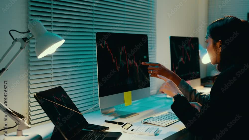 Poster businesswoman is working late, analyzing stock market data on her computer. she is pointing at the s