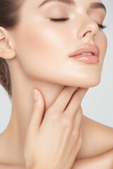 Obraz premium An elegant woman applies cream to her neck and clavicle, showcasing radiant skin and delicate beauty rituals in soft light.