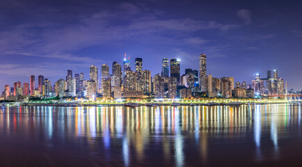 Obraz premium Panoramic view of city skyline and modern buildings scenery in Chongqing at night. Modern city buildings and water reflections.
