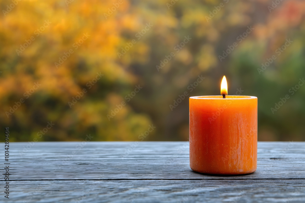 Poster orange scented candle burning on empty table with autumn background
