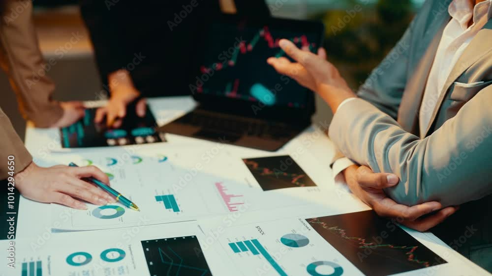Poster business professionals engage in a financial meeting, discussing strategies while analyzing charts a