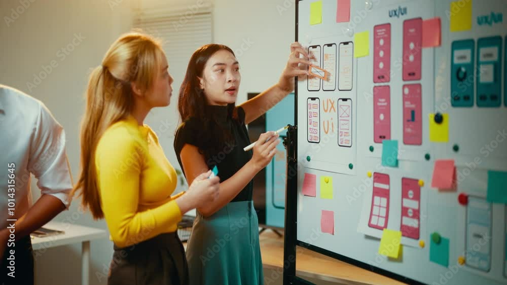 Poster Two women, possibly web designers or developers, are having a discussion about ux ui design. They are both looking at a whiteboard with wireframes and notes on it