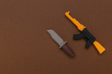 Toy Knife and AK-47 on Brown Surface Symbolizing Playful Adventure and Imagination