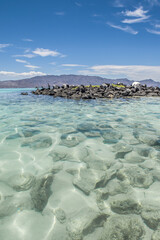 Crystal clear waters of the Sea of ​​Cortes on Coronado Island in Baja California, southern Mexico, with mountains and blue sky in the background