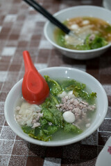 a bowl of fish ball soup with minced meat, dumplings and lettuce