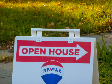 Calgary, Alberta, Canada. Oct 5, 2024. A classic "Open House" sign featuring the REMAX logo, prominently displayed on a sidewalk in a residential area.