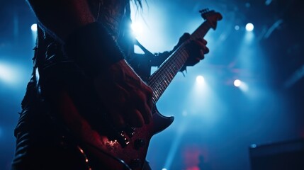 Obraz premium A guitarist performs on stage, illuminated by dramatic lighting, creating an energetic atmosphere.