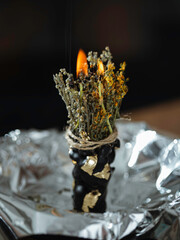 Black candle with herbs, wormwood, St. John's wort., tools for ritual concept photo. Dark witch...