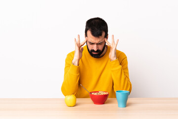 Caucasian man having breakfast in a table with headache.