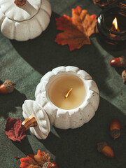 Handmade candles made of coconut and soy wax in a concrete, plaster candlestick with a wooden wick. Scented candle in a pumpkin-shaped candlestick. Selective focus