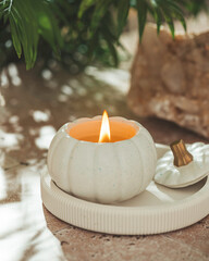 Handmade candles made of coconut and soy wax in a concrete, plaster candlestick with a wooden wick. Scented candle in a pumpkin-shaped candlestick. Selective focus