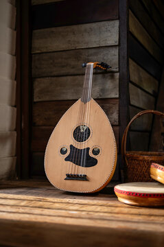 A Malay traditional string musical instrument known as Gambus, stands against a wooden wall with shadow and light effects.