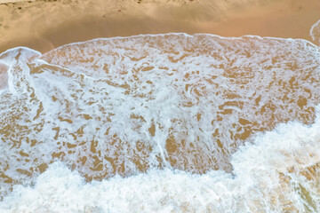 Aerial View of Ocean Waves Crashing on Sandy Beach.