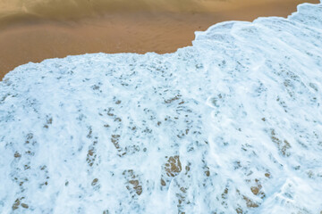 Aerial View of Ocean Waves Crashing on Sandy Beach.