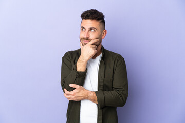 Caucasian man isolated on purple background thinking an idea while looking up