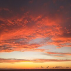 Fototapeta premium The sky at sunset, with vivid orange and red tones reflecting on the water and distant clouds catching the last rays of the sun 