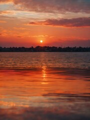 The sky at sunset, with vivid orange and red tones reflecting on the water and distant clouds catching the last rays of the sun

