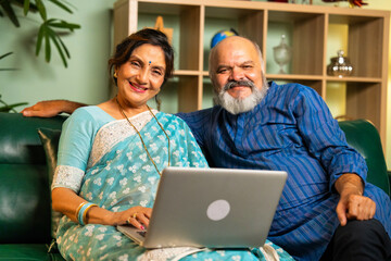 Elderly Indian couple using a laptop for online shopping, video calls, or browsing at home