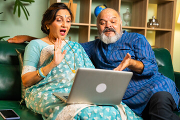 Elderly Indian couple using a laptop for online shopping, video calls, or browsing at home