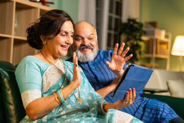 Elderly Indian couple using tablet computer for video call at home