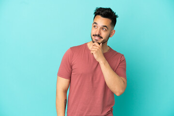 Young caucasian man isolated on blue background looking up while smiling