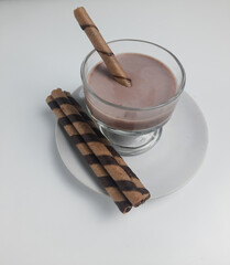 Wafer rolls or tubes and chocolate milk in glass jar on isolated background