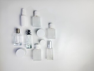 Close-up of glass perfume bottle and round jar on isolated white background