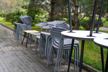 stack of colorful plastic outdoor furniture, neatly arranged on the sidewalk outside a restaurant, symbolizing a vibrant atmosphere and inviting dining experience
