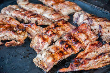 Grilling pork ribs on barbecue grill closeup