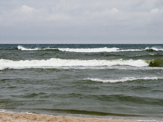 Tranquil Seascape with Waves Crashing on Sandy Beach Under Overcast Sky