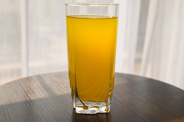 Szklanka soku pomarańczowego stojąca na stoliku w restauracji przy oknie, jedzenie na mieście 