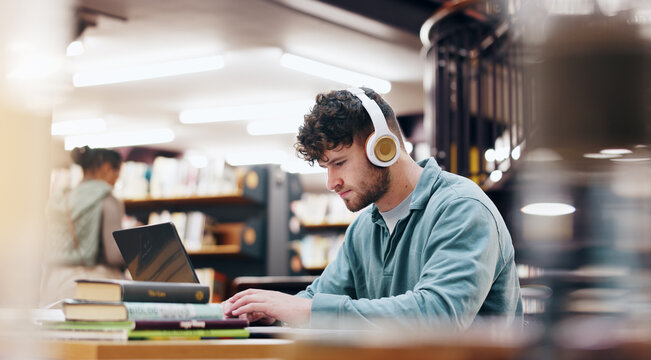 Man, student and typing on laptop in library for research information, university website and study schedule. Person, online course and headphones of education project, exam results and podcast audio