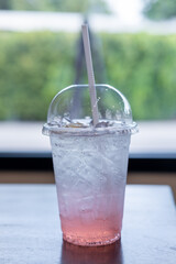 A cup of lychee lemon soda on the table, with bokeh background of the cafe