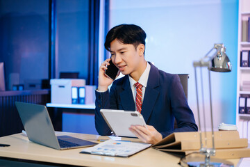 Asian Businessman analyzing reports in a modern office, working on a computer. Perfect for...