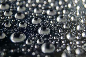 Side view of raindrops forming patterns on a smooth surface. Fresh rain texture