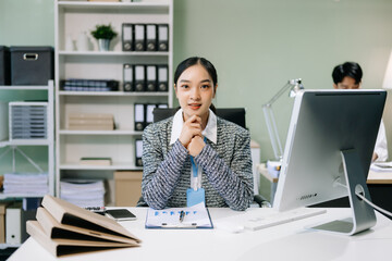 Young attractive Asian female office worker business suits smiling at camera with working