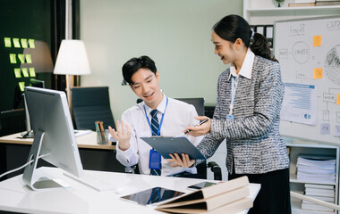 Two young Asian professionals engaged in teamwork and business discussions in office
