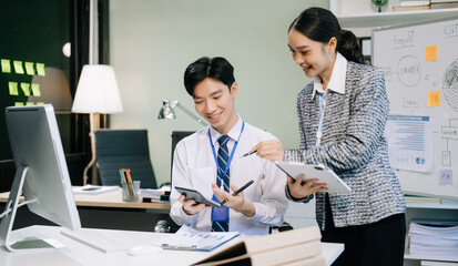 Two young Asian professionals engaged in teamwork and business discussions in office