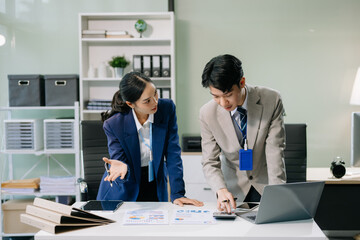 Two young Asian professionals engaged in teamwork and business discussions in office