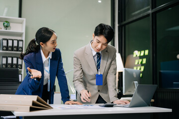 Two young Asian professionals engaged in teamwork and business discussions in office