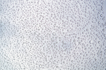 Close-up of droplets clustering on a glass surface after rain. Water texture concept
